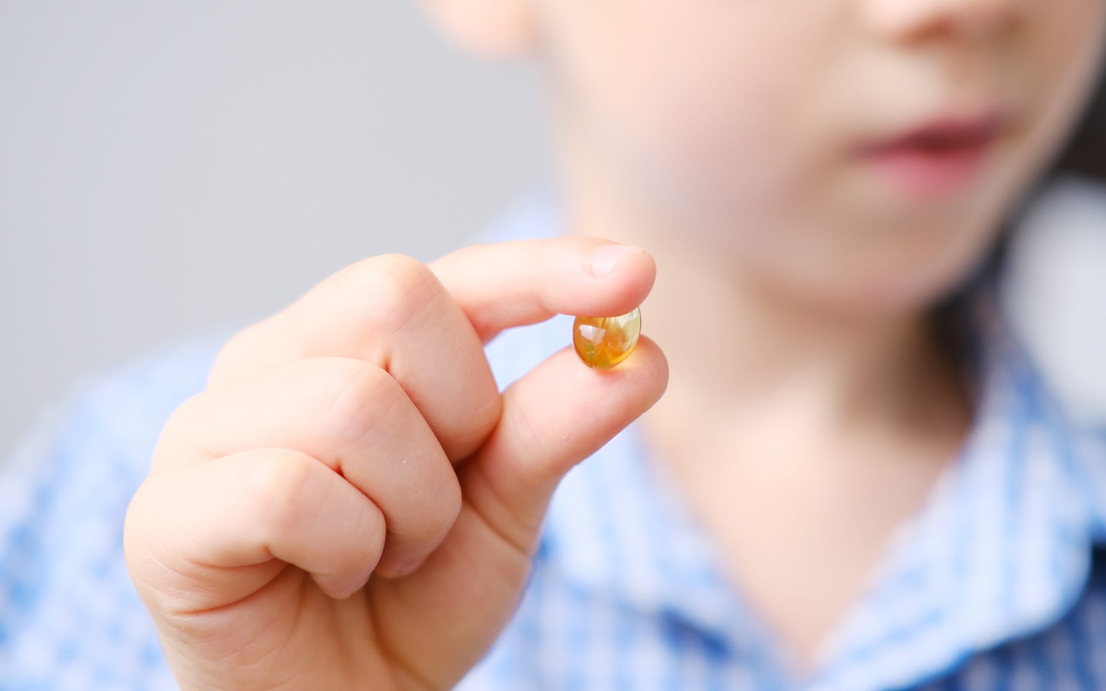 kid holding fish oil capsule