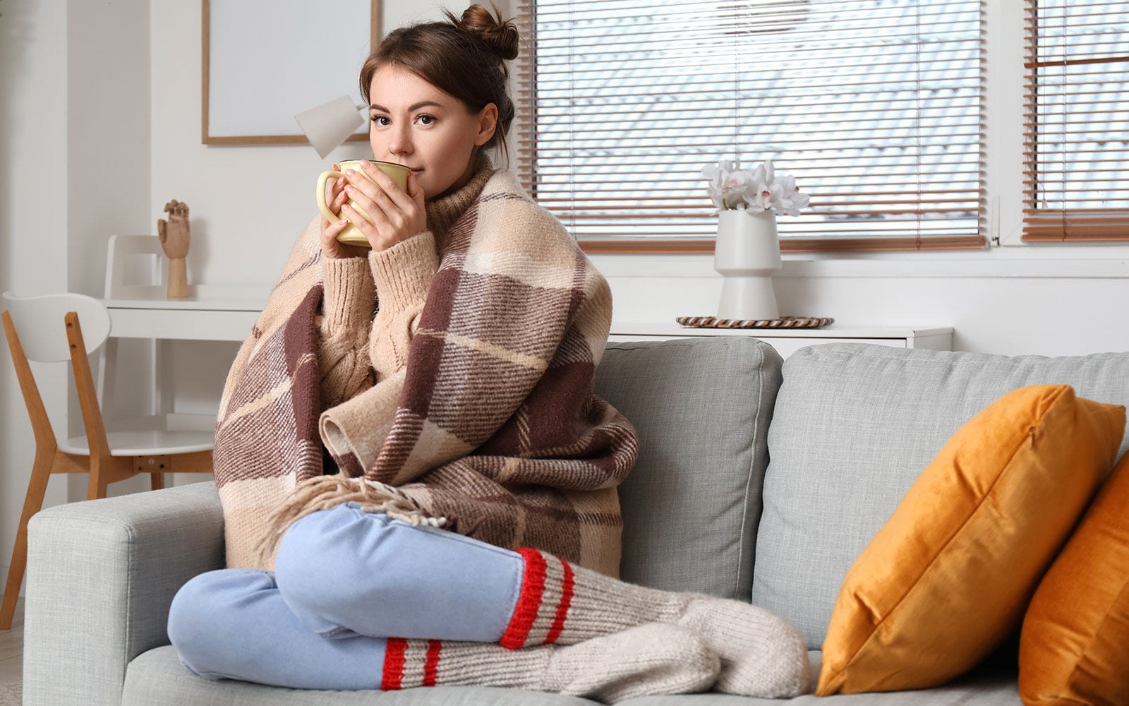 woman staying warm with hot drink and blanket